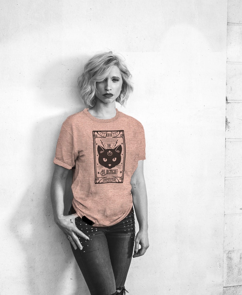 May include: A woman wearing a pink t-shirt with a black cat tarot card graphic. The card reads "XIII The Blackcat - Shadow Path".