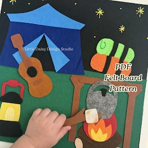 May include: A felt board pattern featuring a camping scene with a blue tent, a brown guitar, a yellow lantern, a campfire with a grey kettle, and sleeping bags against a black night sky with yellow stars. Text reads Little Daisy Design Studio.