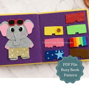 May include: A felt busy book page featuring a gray elephant wearing red sunglasses and gold glitter shorts. The purple page includes various rectangular felt shapes in red, green, yellow with a sunflower, pink, rainbow, blue with a star, and brown.