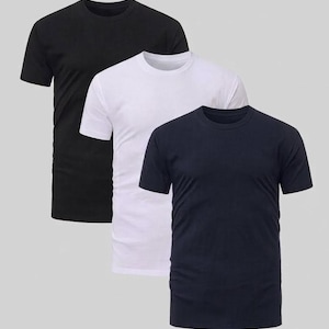 May include: A set of three short-sleeved crew neck t-shirts in solid colors. The collection includes one black t-shirt, one white t-shirt, and one navy blue t-shirt. Each garment features a standard fit with a round neckline and short sleeves.