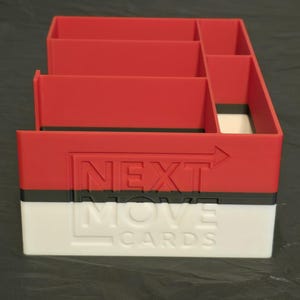 Puede incluir: Un organizador de tarjetas rectangular de pl&aacute;stico rojo, negro y blanco con m&uacute;ltiples compartimentos interiores. El exterior frontal presenta el texto en relieve NEXT MOVE CARDS con una flecha hacia la derecha sobre las secciones roja y blanca.