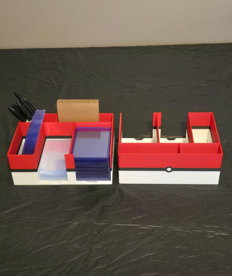 Puede incluir: Dos organizadores de almacenamiento rectangulares con un dise&ntilde;o en rojo, blanco y negro con un detalle circular en el frente. El organizador izquierdo contiene marcadores negros, fundas de pl&aacute;stico transparente y tarjetas marrones.