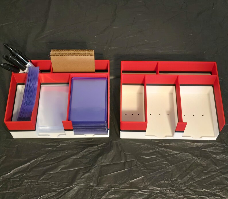 Puede incluir: Dos organizadores rectangulares de pl&aacute;stico en rojo, blanco y negro con m&uacute;ltiples compartimentos. El organizador izquierdo contiene marcadores negros, divisores de cart&oacute;n marr&oacute;n y fundas para tarjetas azules.