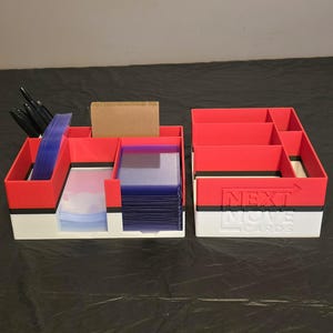 Puede incluir: Un organizador de tarjetas de pl&aacute;stico rojo, negro y blanco con m&uacute;ltiples compartimentos. La secci&oacute;n izquierda contiene fundas para tarjetas azules y marcadores negros, mientras que la derecha presenta el texto NEXT MOVE CARDS en relieve.
