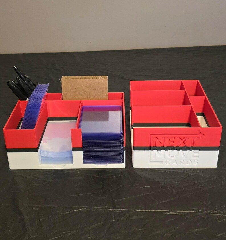 Puede incluir: Un organizador de tarjetas de pl&aacute;stico rojo, negro y blanco con m&uacute;ltiples compartimentos. La secci&oacute;n izquierda contiene fundas para tarjetas azules y marcadores negros, mientras que la derecha presenta el texto NEXT MOVE CARDS en relieve.