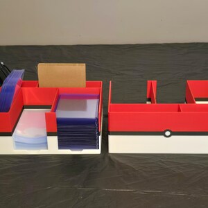 Puede incluir: Dos organizadores de escritorio rectangulares con un esquema de color rojo, blanco y negro con un detalle circular central. El organizador izquierdo contiene bol&iacute;grafos negros, fundas para tarjetas azules y un bloque rectangular marr&oacute;n.