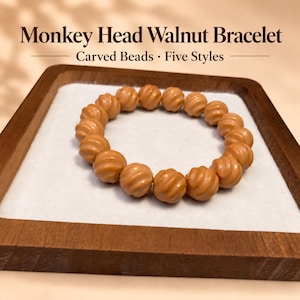 May include: A bracelet made of light brown, spherical monkey head walnut beads with a carved, spiraling texture. The text "Monkey Head Walnut Bracelet" and "Carved Beads · Five Styles" is displayed above the circular arrangement of beads.