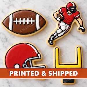 May include: Four sugar cookies shaped like American football items: a brown football with white laces, a player in a red jersey running with a ball, a red football helmet, and a yellow goal post. The cookies feature detailed icing designs.