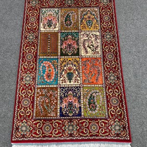 May include: A rectangular area rug featuring a deep red border with intricate floral patterns and a central grid of twelve distinct panels. Each panel displays unique botanical and paisley motifs in vibrant colors including blue, orange, green, and gold, finished with white fringe.