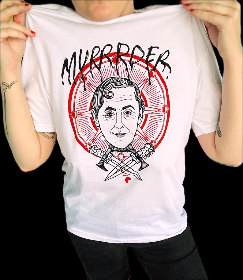 May include: A white t-shirt featuring a graphic print of a person's head centered within a red circular emblem with radiating lines. Below the head are two crossed daggers. The text "MYRRROER" is printed in black above the circular design.