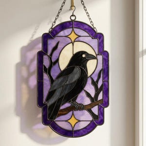 Puede incluir: Un panel de vidriera rectangular que muestra un cuervo negro posado en una rama marrón frente a una luna amarilla pálida. El fondo es de color violeta claro con bordes violeta oscuro y estrellas amarillas, suspendido por una cadena.