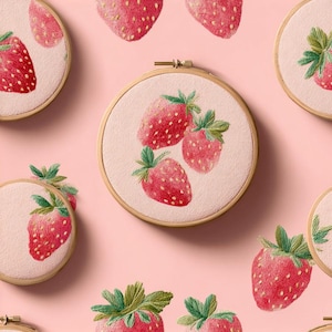 Könnte beinhalten: Eine Sammlung runder hölzerner Stickrahmen mit Stoff, der ein sich wiederholendes Muster aus roten Erdbeeren mit grünen Blättern auf hellrosa Hintergrund zeigt. Jeder Rahmen fasst einen Ausschnitt des Erdbeermusters mit sichtbaren Stichen ein.