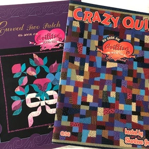 May include: Two quilting pattern books with purple and black covers. The first book is titled "Curved Two Patch as seen on Quilting from the Heartland". The second book is titled "Crazy Quilt as seen on Quilting from the Heartland" and has a colorful patchwork quilt design on the cover. The book is hosted by Sharlene Jorgenson.