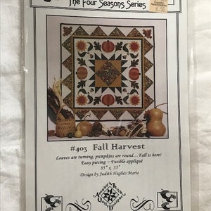 Pode incluir: Um padrão de acolchoado para um edredom de colheita de outono. O padrão apresenta um design de patchwork com abóboras, folhas e outros elementos outonais. O padrão é intitulado "#403 Fall Harvest" e faz parte da "The Four Seasons Series".