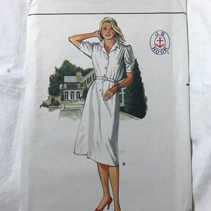 Può includere: Un cartamodello vintage per un abito bianco con bottoni e cintura. Il cartamodello è di Butterick ed è di taglia 14. Il cartamodello è per un design di J.G. Hook.