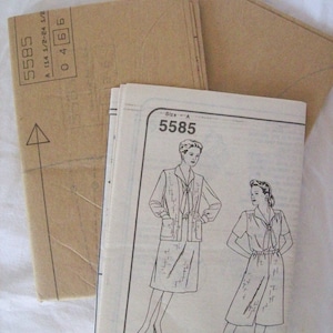 May include: A sewing pattern for two outfits, both with a tie at the neck. The pattern is for size A and is numbered 5585.