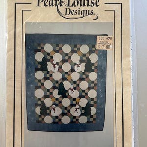 May include: A quilting pattern for a snowball quilt with a blue background and white snowmen, green trees, and yellow stars. The pattern is titled "#278 SNOWBALL QUILT" and measures 52" x 64".