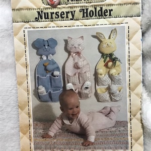 Może przedstawiać: Wzorzec szycia vintage do organizatora do pokoju dziecięcego z trzema wzorami: psem, kotem i królikiem. Wzór pochodzi od Patch Press i ma numer 3408. Wzór zawiera pełnowymiarowe elementy dla wszystkich trzech wzorów.