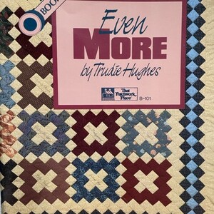 May include: Book cover for a quilting pattern book titled "Even More" by Trudie Hughes. The cover features a patchwork quilt design with a variety of colors and patterns. The book is part of a series, as indicated by the "Book Three" label.