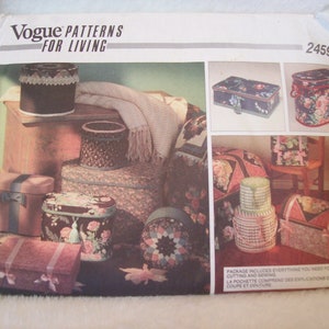 May include: A vintage Vogue Patterns for Living sewing pattern, number 2459, featuring a variety of storage boxes and containers with floral and geometric designs. The pattern includes instructions for cutting and sewing.