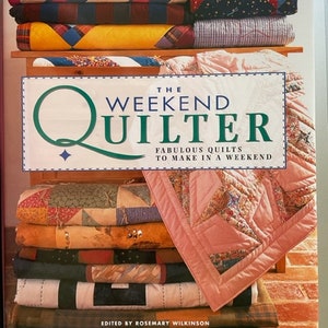 Puede incluir: Un libro titulado "The Weekend Quilter: Fabulous Quilts to Make in a Weekend" de Rosemary Wilkinson. La portada del libro presenta una pila de colchas coloridas con una variedad de patrones.