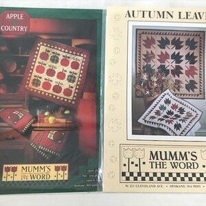 May include: Two quilt patterns, "Apple Country" and "Autumn Leaves", with instructions for making a quilt. Both patterns feature a red, white, and green color scheme. The patterns are from "Mumm's The Word" quilting company.