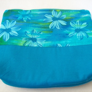 May include: A turquoise zippered pouch with a blue floral print. The pouch has a solid turquoise bottom.