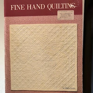 May include: A book titled "Fine Hand Quilting" by Diana Leone. The cover features a close-up of a quilted fabric with a diamond pattern in a cream color.