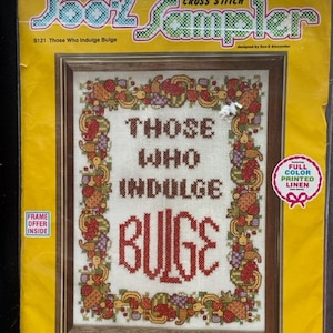 May include: A cross stitch sampler kit featuring a colorful design with the text "Those Who Indulge Bulge". The kit includes full color printed linen, embroidery floss, a needle, and instructions. It is suitable for a 9 x 12 inch frame.