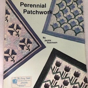 May include: A book titled "Perennial Patchwork" by Jackie Robinson. The cover features three quilt designs with a variety of colors and patterns, including blue, green, black, and white.