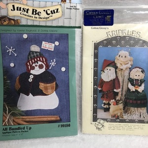 May include: Two applique pattern packets for creating a snowman and a trio of Christmas characters. The snowman pattern is titled "All Bundled Up" and features a snowman wearing a blue and white patterned jacket. The Christmas character pattern is titled "Kringles" and features a Santa, angel, and a girl.