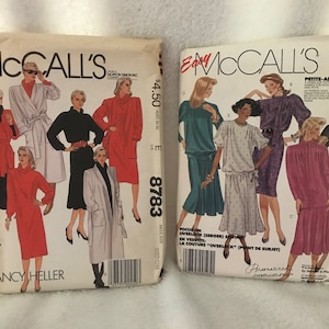 May include: Two sewing pattern envelopes with McCall's branding. The left envelope features a red, black, and white dress pattern with the text "Nancy Heller". The right envelope features a blue, green, and white dress pattern with the text "Petite-Able".