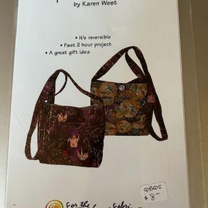 Pode incluir: Um padrão para uma bolsa reversível, intitulado "Split Purse-onality" por Karen West. A imagem mostra dois designs de bolsas com estampas florais e de guindastes. O texto indica que é reversível e um projeto rápido de 2 horas.