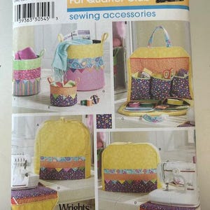 May include: Simplicity Fat Quarter Club sewing accessories pattern. The pattern features various sewing accessories, including storage baskets, a sewing machine cover, and a sewing kit. The accessories have a yellow, pink, and purple colour scheme.