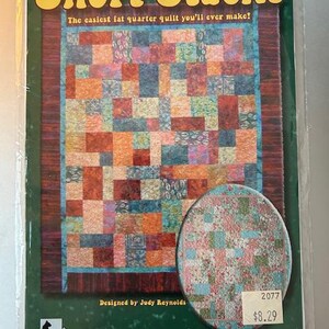 May include: A package for a quilt pattern titled "Short Stacks." The pattern features a colorful patchwork design with squares of various colors. The text "The easiest fat quarter quilt you'll ever make!" is displayed above the quilt image.
