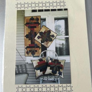 May include: A printed image of a quilt pattern titled "Mostly Strips" Garden Path. The image shows a table runner, small topper, and pillows with a patchwork design. The table runner measures 16 1/2 x 40 1/2 inches, and the topper/pillows are 16 x 16 inches.