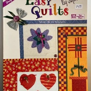 Może przedstawiać: Okładka książki "Easy Quilts" autorstwa Jupiter, przedstawiająca kolorowy patchwork z sercami, kwiatami i kratą. Książka jest częścią serii "Designer Series" i została napisana przez Mary Beth Maison.