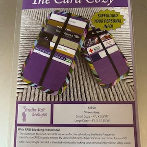 May include: The Card Cozy, a purple card holder with a black elastic band, designed to safeguard personal info. The package includes two sizes: Small Cozy - 10.16cm L x 13.97cm W and Large Cozy - 10.16cm L x 18.1cm W. Features RFID-blocking protection.