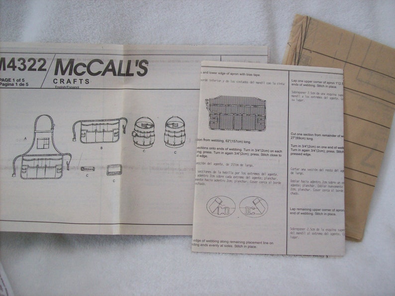 May include: A black and white sewing pattern for a utility apron with multiple pockets. The pattern is labelled "M4322 McCall's Crafts".