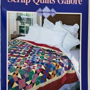 May include: A book cover titled "Scrap Quilts Galore" with the subtitle "Quilts Made Easy." The cover features a colorful quilt on a bed with white pillows. The bottom of the cover reads "Designs • Patterns • Techniques."