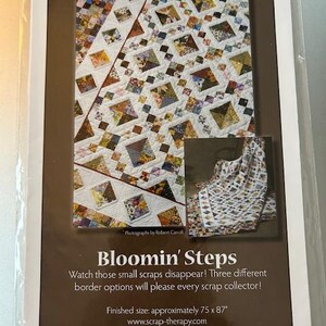 May include: A package for a quilt pattern titled "Bloomin' Steps" by Scrap Therapy. The pattern features a quilt design with colorful square patches. The finished size is approximately 75 x 87 inches. The package includes the text "Watch those small scraps disappear!"