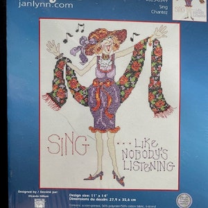 Puede incluir: Un patrón de punto de cruz con una mujer cantando con una bufanda. El patrón se titula "Sing...Like Nobody's Listening".