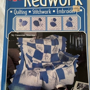 Pode incluir: Um livro intitulado "Redwork in Blue" de Laurene Sinema, que apresenta um edredom com um padrão xadrez azul e branco e bordados brancos. A capa do livro também inclui uma pequena ilustração de uma mulher com um vestido azul e um chapéu branco.