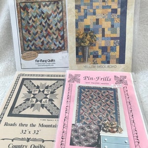 Könnte beinhalten: Vier Quiltmuster mit Anleitungen. Die Muster sind betitelt "Braids on Parade", "Yellow Brick Road", "Roads thru the Mountain" und "Pin-Frills".