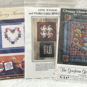 Puede incluir: Tres patrones de acolchado a la venta. El primer patrón se llama "Spring Fantasy" y presenta una corona en forma de corazón. El segundo patrón se llama "Attic Window and Snails Tails Mini-Quilt" y presenta un diseño geométrico. El tercer patrón se llama "Chuggy Choo-Choo Quilt" y presenta un tren con un vagón de cola rojo.