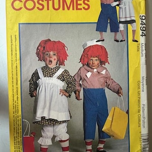 May include: A McCall's Costumes sewing pattern for Raggedy Ann and Andy costumes. The pattern features illustrations of the costumes, including a dress, overalls, and wigs. The package is yellow with red text.