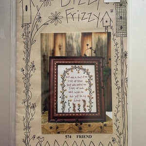 May include: Cross stitch pattern with a brown wooden frame and a white background. The pattern features a floral arch with the text "Just walk in front of me, I may not follow. Don't walk behind me, I may not lead. Walk beside me and just be my friend."