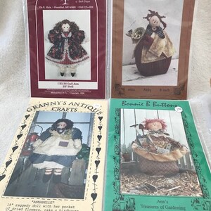 Peut inclure: Quatre patrons de poupées différents pour la couture. Les patrons sont imprimés sur du papier et présentent des illustrations des poupées. Les patrons sont intitulés "Gall Ann", "Abby", "Annabelle" et "Les trésors de jardinage d'Ann".