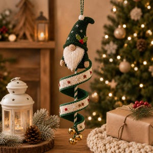 May include: A hanging crochet gnome ornament featuring a dark green pointed hat with white snowflake embroidery and holly leaves. The gnome has a long white beard and is attached to a spiraling cream and green ribbon decorated with small bells.