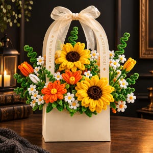 May include: A cream-colored paper gift bag with a sheer ribbon bow at the top, featuring the text 'JUST FOR YOU' on both sides. The bag is filled with a bouquet of handcrafted pipe cleaner flowers, including yellow sunflowers, orange tulips, and small white daisies.